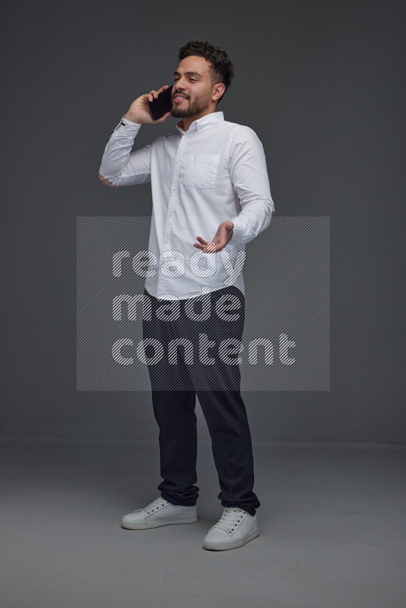 A man wearing smart casual talking in the phone eye level on a gray background
