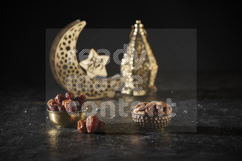 Dates in a metal bowl with almonds beside golden lanterns in a dark setup