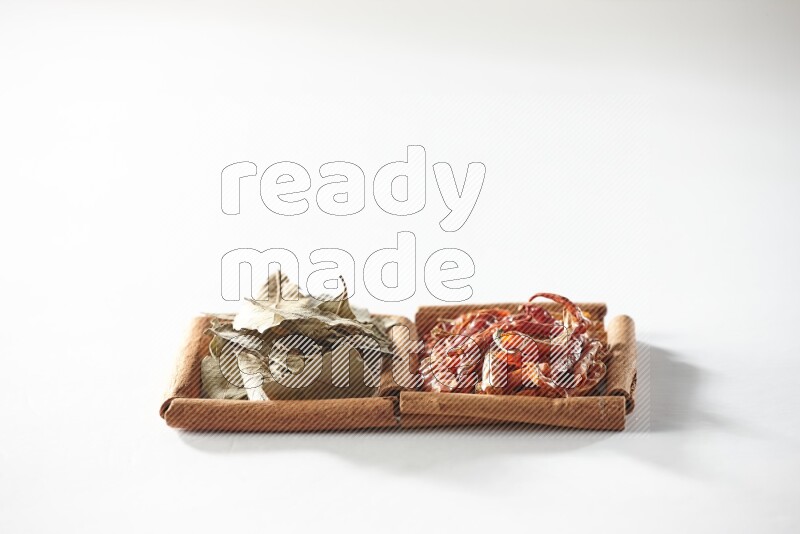 2 squares of cinnamon sticks full of dried red chilis and bay laurel leaves on white flooring