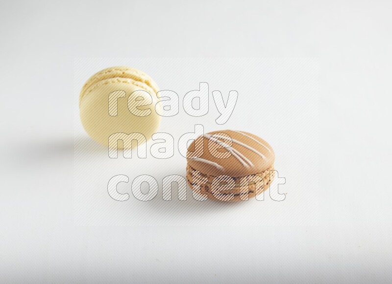 45º Shot of of two assorted Brown Irish Cream, and Yellow Vanilla macarons on white background