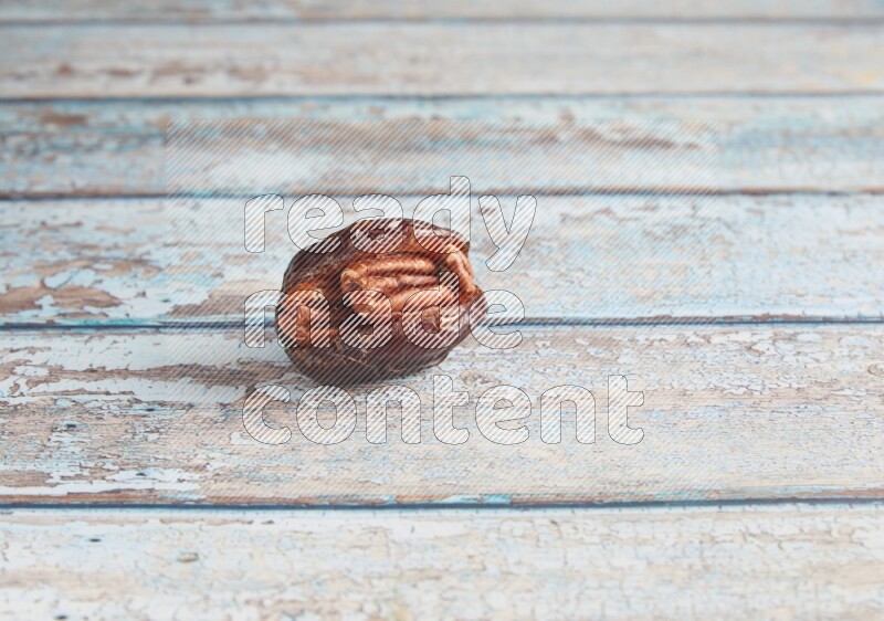pecan stuffed madjoul date on a light blue wooden background