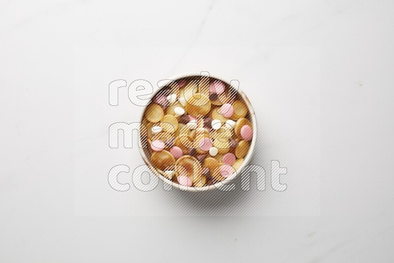 Top-view shot of mixed chocolate chips cereal pancakes in a round bowl on white background