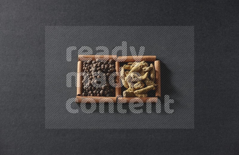 2 squares of cinnamon sticks full of allspice and turmeric fingers on black flooring