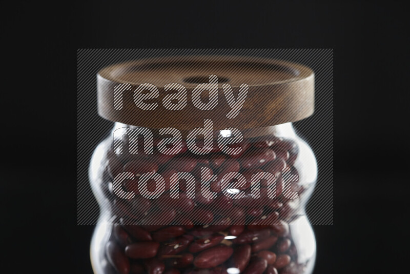 Red kidney beans in a glass jar on black background