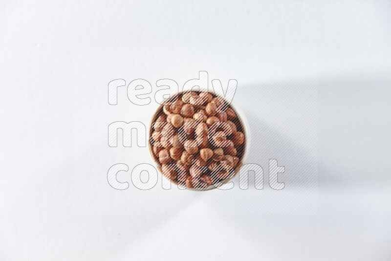 A beige ceramic bowl full of peeled hazelnuts on a white background in different angles