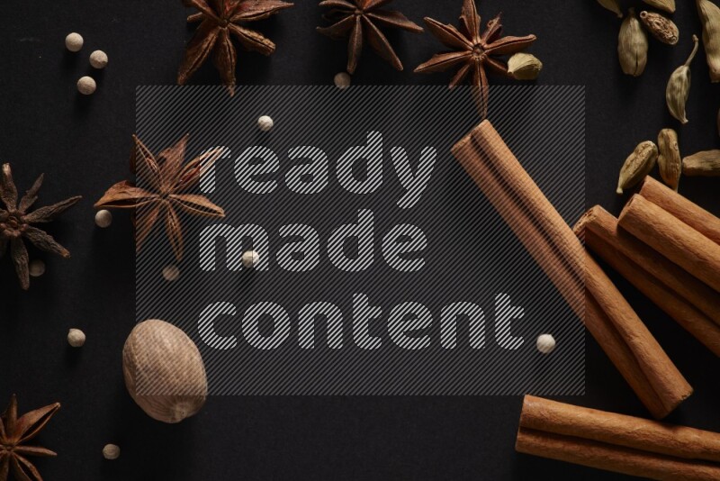 Cinnamon sticks, cardamom, star anise, nutmeg and white peppers on a black background