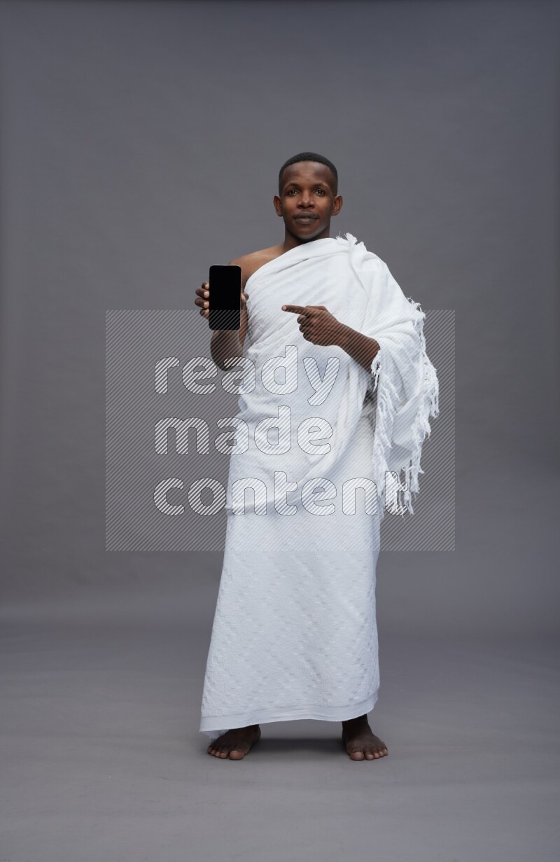 A man wearing Ehram Standing showing phone to camera on gray background