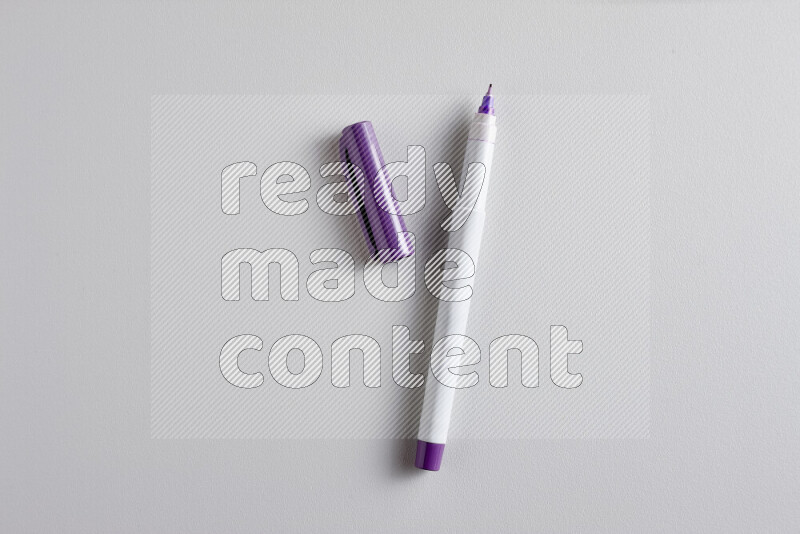 A close-up showing an open single coloring pen with a cap on grey background