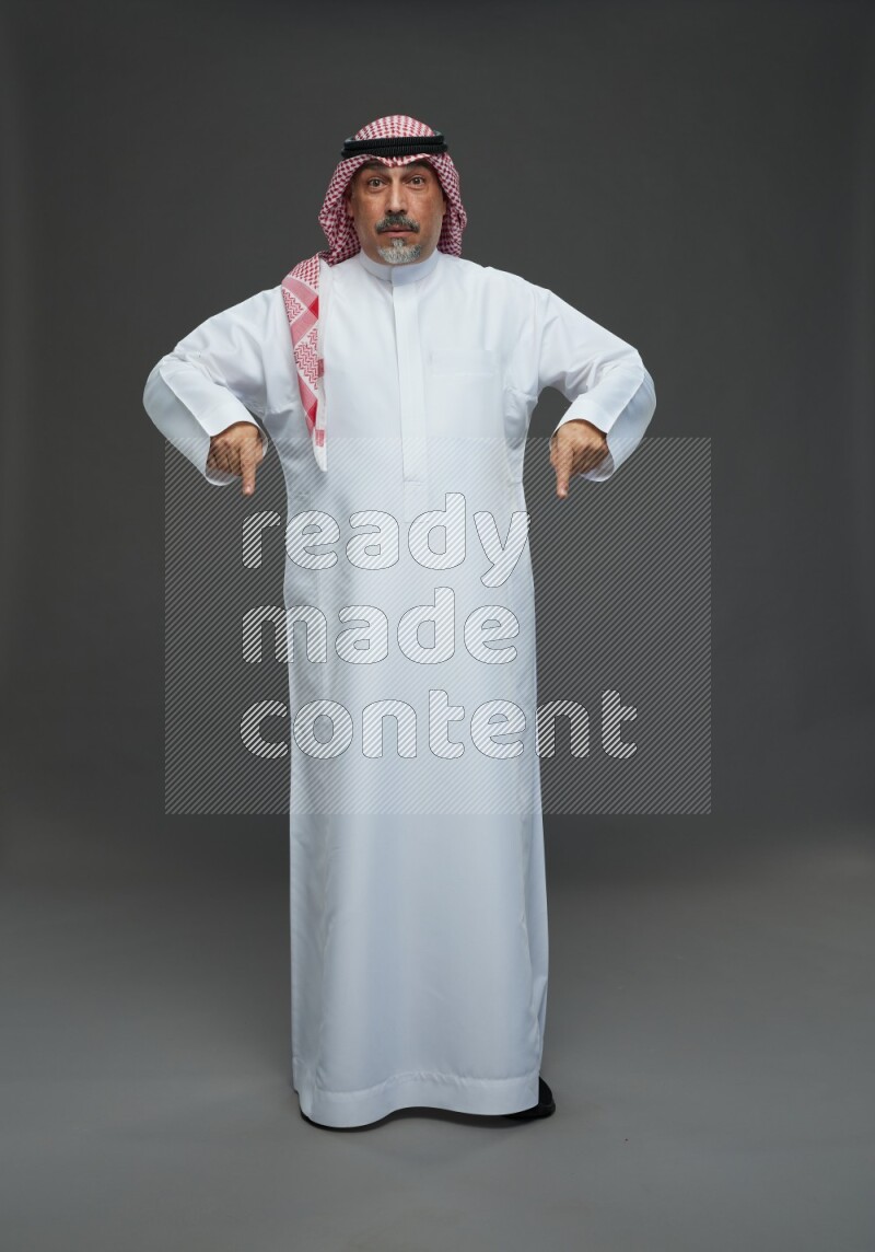 Saudi man with shomag Standing Interacting with the camera on gray background