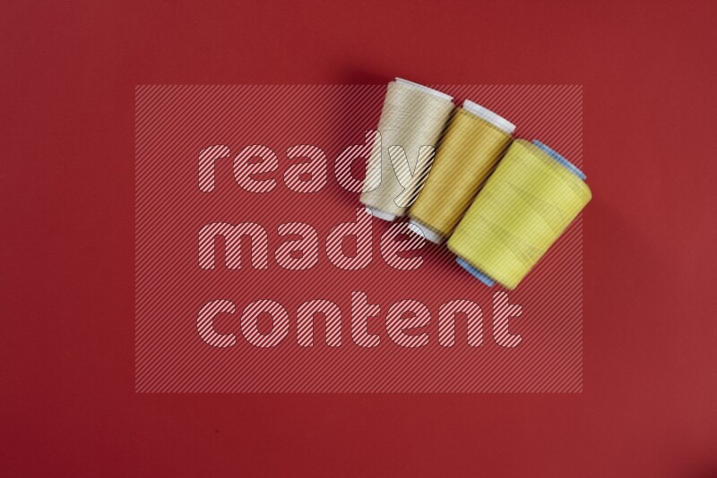 A yellow collection of sewing and tailoring tools arranged on a red background