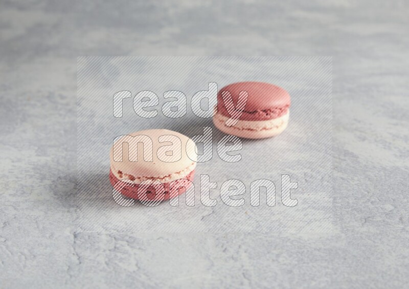45º Shot of two Pink Litchi Raspberry macarons  on white  marble background