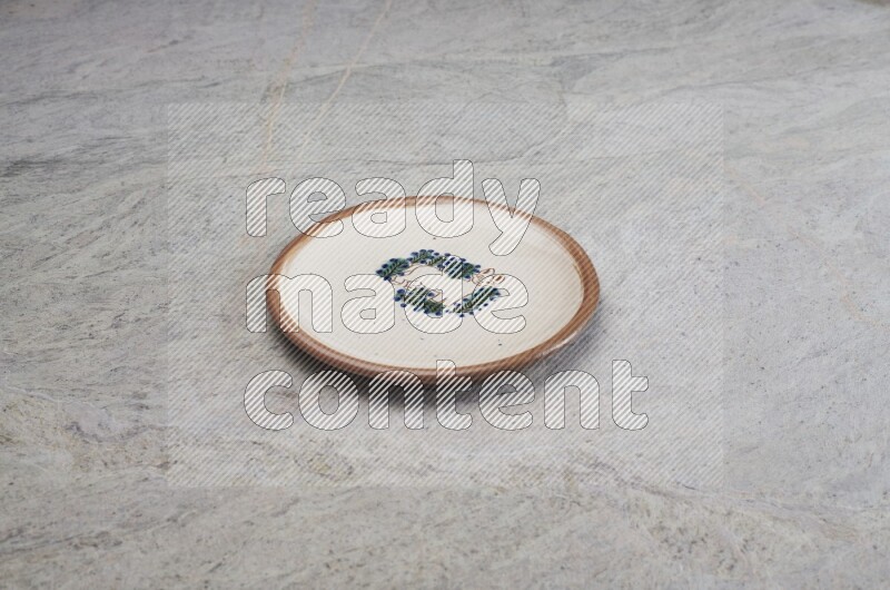 A decorative pottery plate on grey marble background