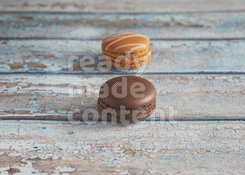 45º Shot of of two assorted Brown Irish Cream, and Brown Dark Chocolate macarons on light blue background