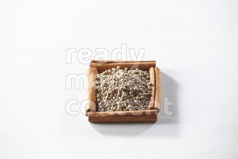 A single square of cinnamon sticks full of white pepper on white flooring