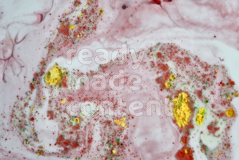 The image captures a splatter of yellow, red and green paint over a white backdrop