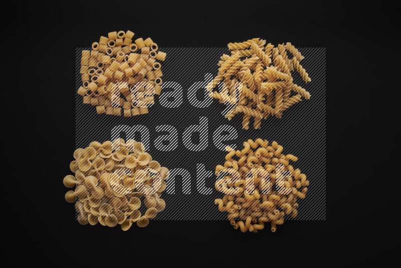 Different pasta types in bunches on black background