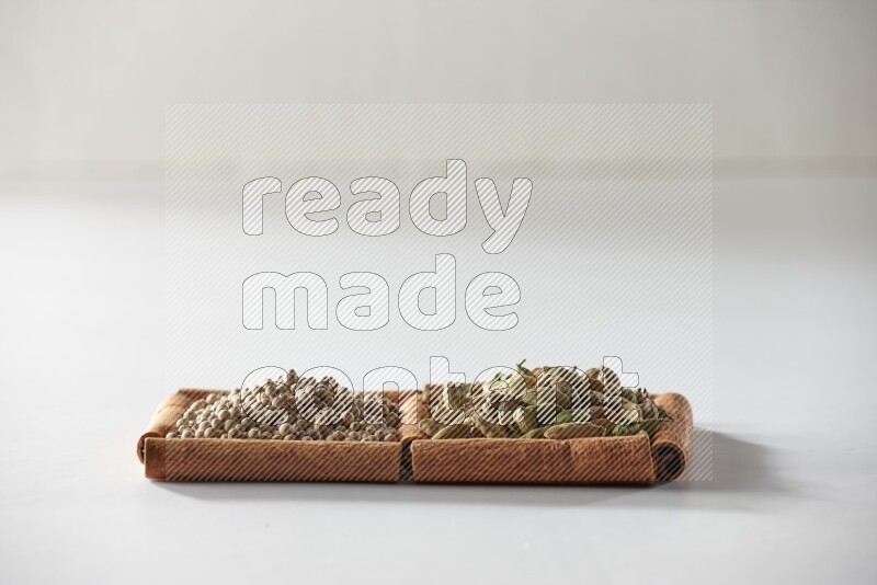 2 squares of cinnamon sticks full of cardamom and white pepper on white flooring