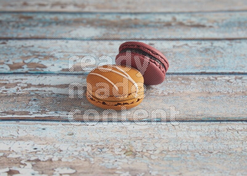 45º Shot of of two assorted Brown Irish Cream, and Red Cherry macarons  on light blue background