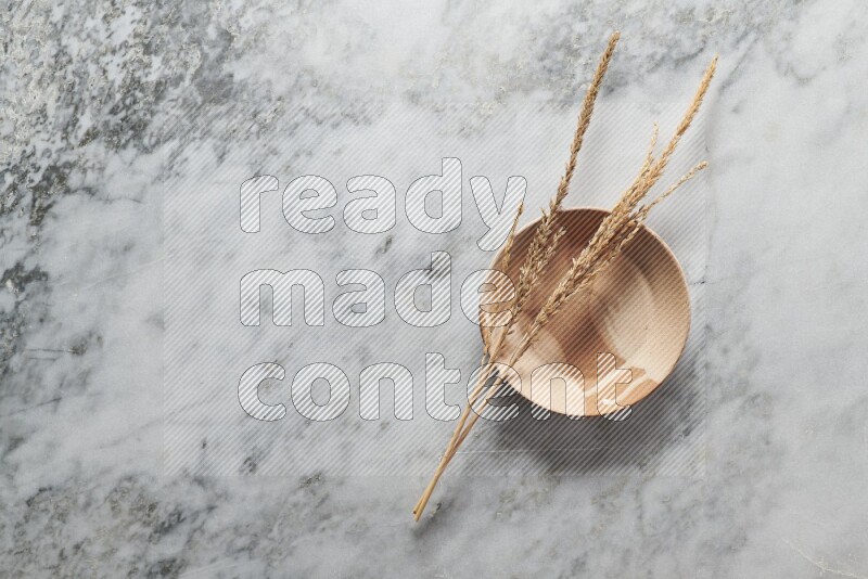 Wheat stalks on multicolored pottery plate on grey marble background