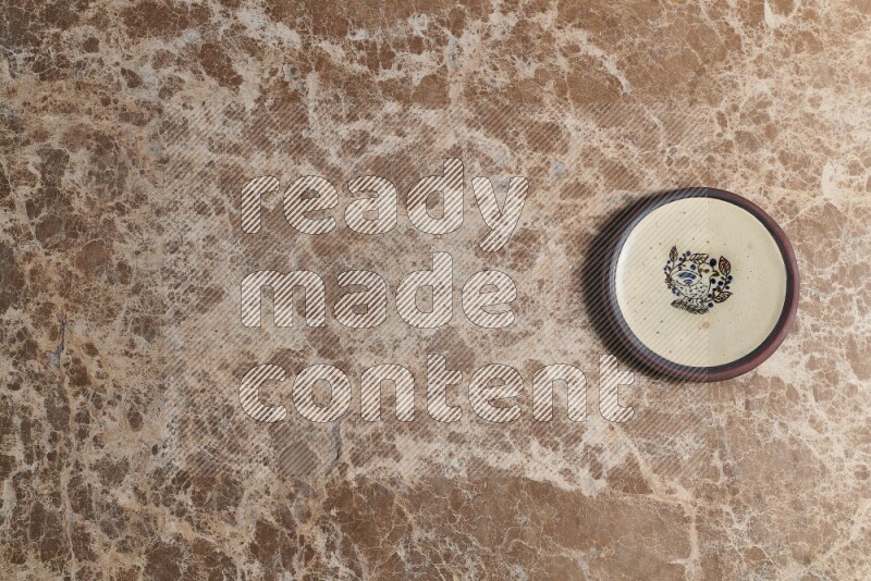 A decorative pottery plate on beige marble background