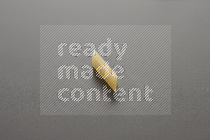 Mini penne pasta on grey background