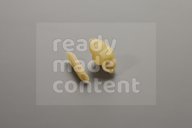Mini penne pasta with other types of pasta on grey background