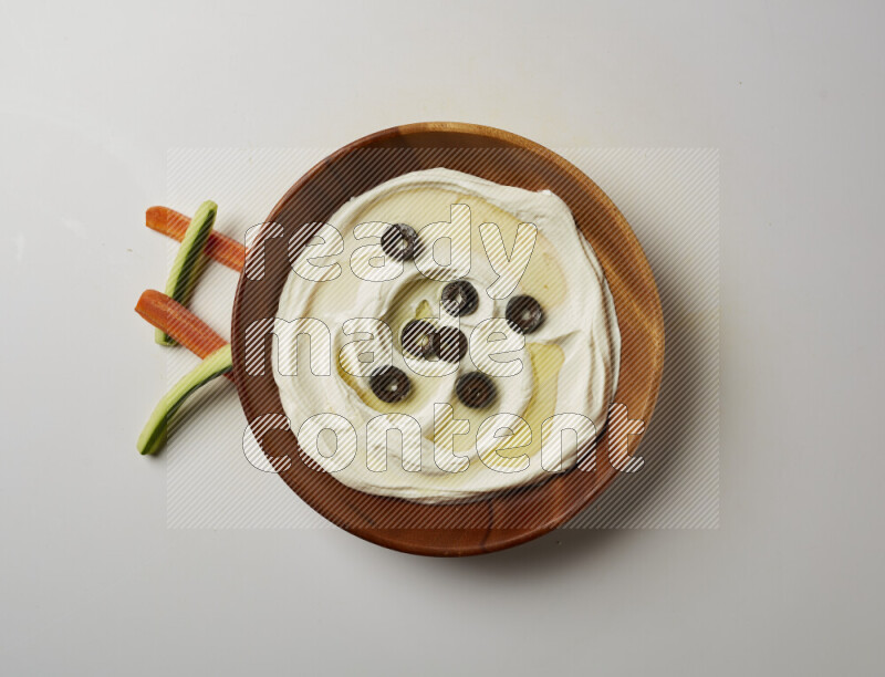 Lebnah garnished with sliced olives in a wooden plate on a white background