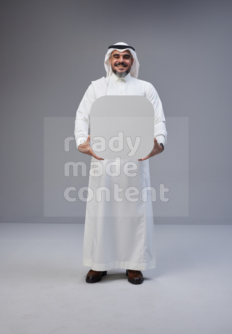 Saudi man Wearing Thob and white Shomag standing holding social media sign on Gray background