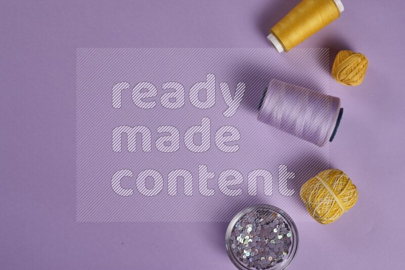 A yellow and purple collection of sewing and tailoring tools arranged on a purple background