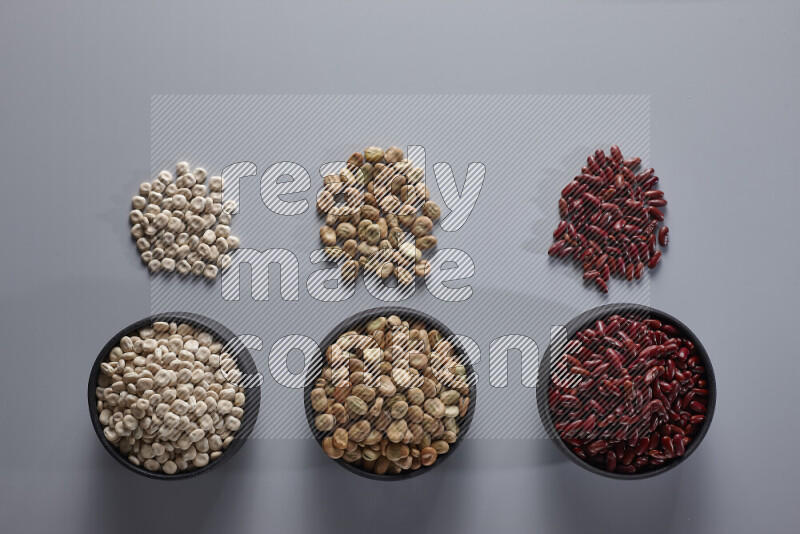 Legumes in pottery bowls on light grey background