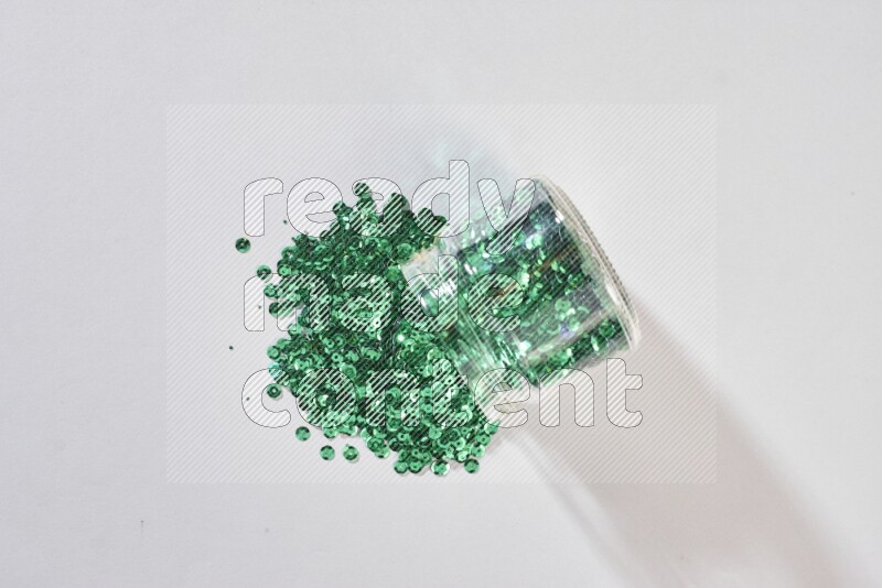 Colored flat sequins in a glass jar on grey background
