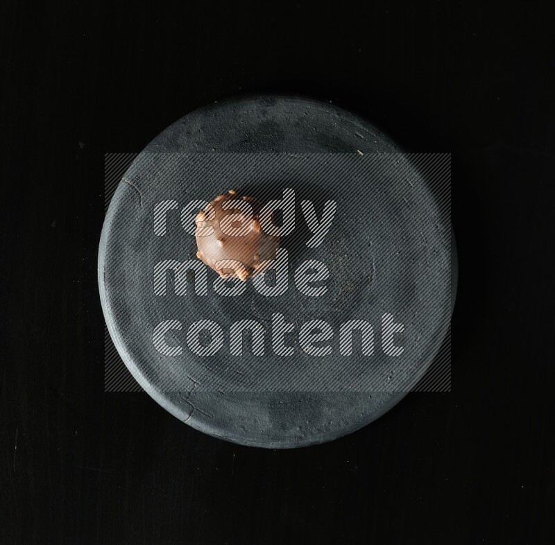 تشكيلة من الحلويات في طبق فخاري أسود على خلفية سوداء