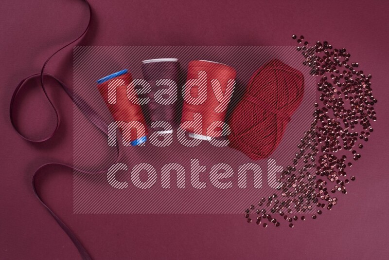 مجموعة من أدوات الخياطة والتفصيل حمراء اللون على خلفية حمراء