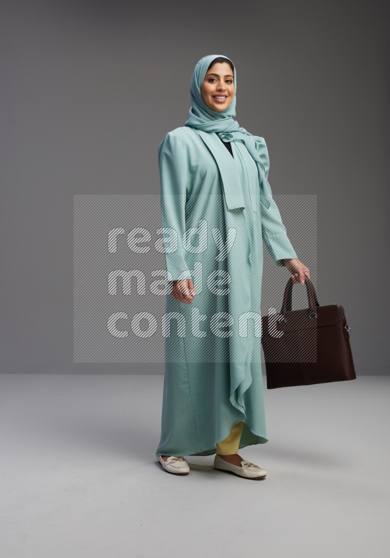 Saudi Woman wearing Abaya standing holding bag on Gray background