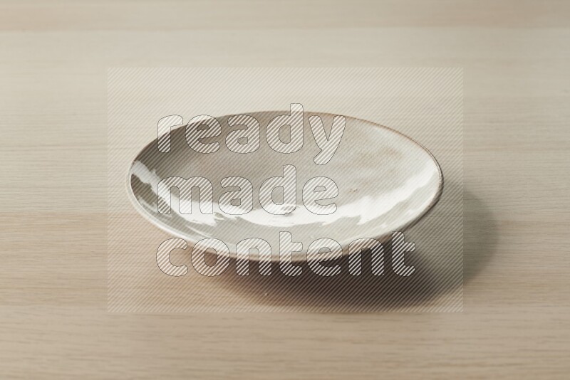 A beige pottery plate on light wooden background