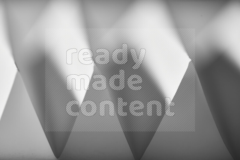 A close-up abstract image showing sharp geometric paper folds in grey gradients