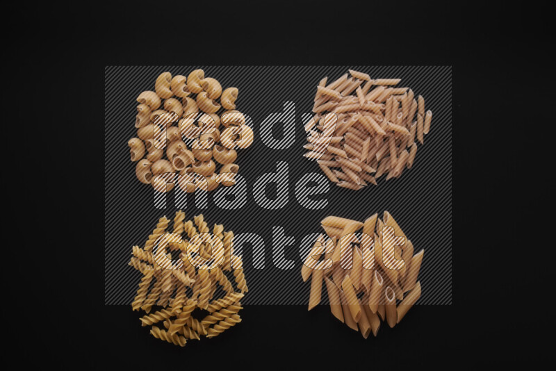 Different pasta types in bunches on black background