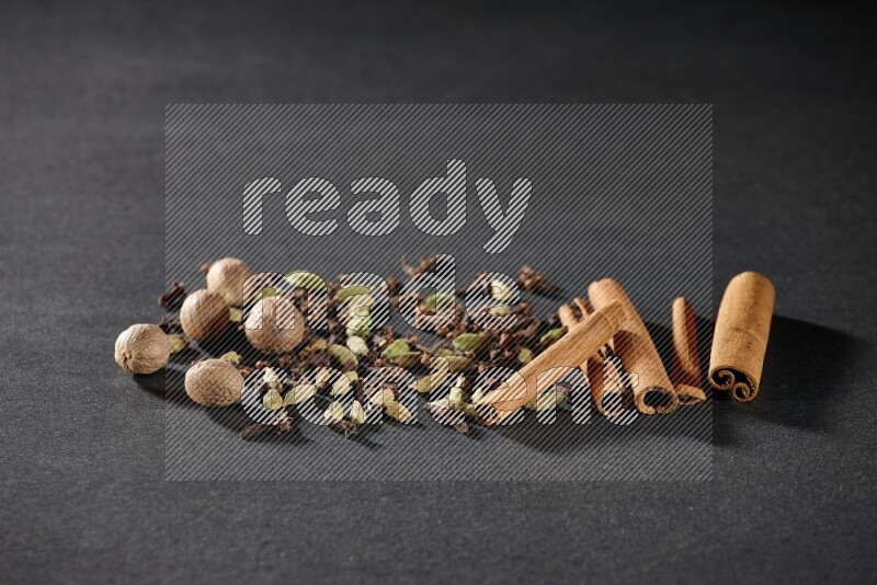 الهيل والقرنفل وجوزة الطيب وأعواد القرفة على خلفية سوداء