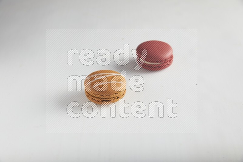 45º Shot of of two assorted Brown Irish Cream, and Red Velvet macarons on white background