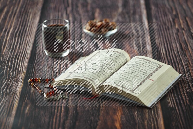 Quran with dates, prayer beads and different drinks all placed on wooden background