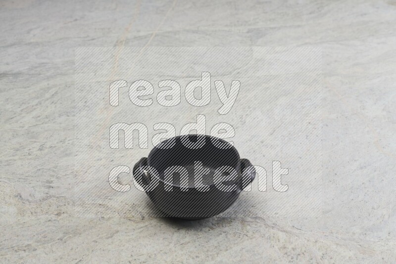 A black pottery bowl on grey marble background