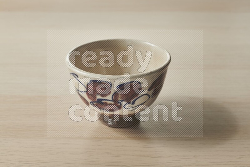 A decorative pottery bowl on light wooden background