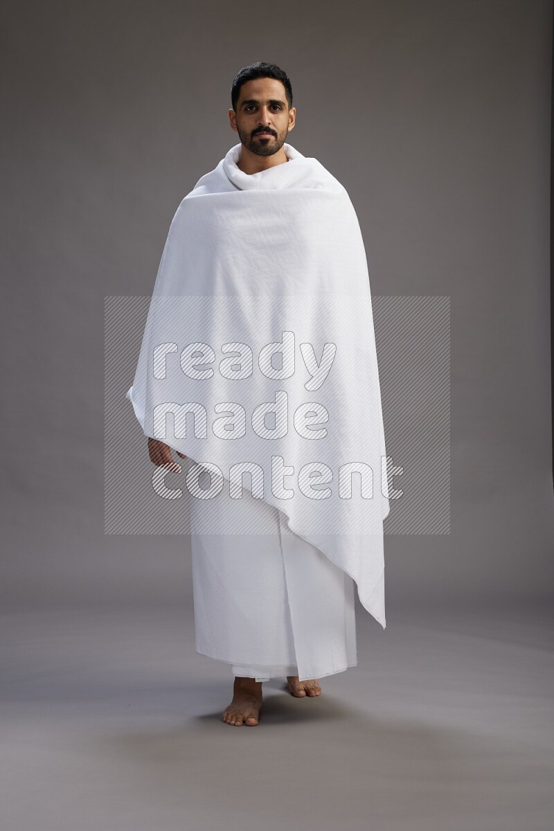 A man wearing Ehram Standing Interacting with the camera on gray background