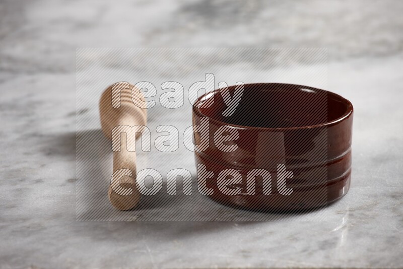 Brown pottery bowl with wooden honey dipper on the side on grey marble background