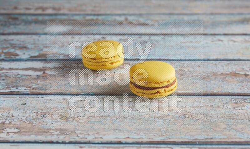 45º Shot of two Yellow Lemon macarons on light blue wooden background
