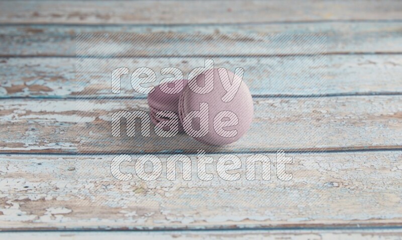 45º Shot of two Purple Blueberry macarons on light blue wooden background