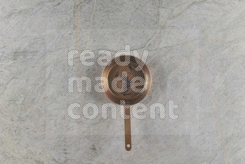 A small copper pan on grey marble background