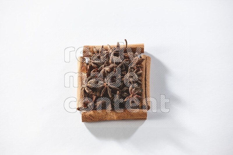 A single square of cinnamon sticks full of star anise on white flooring