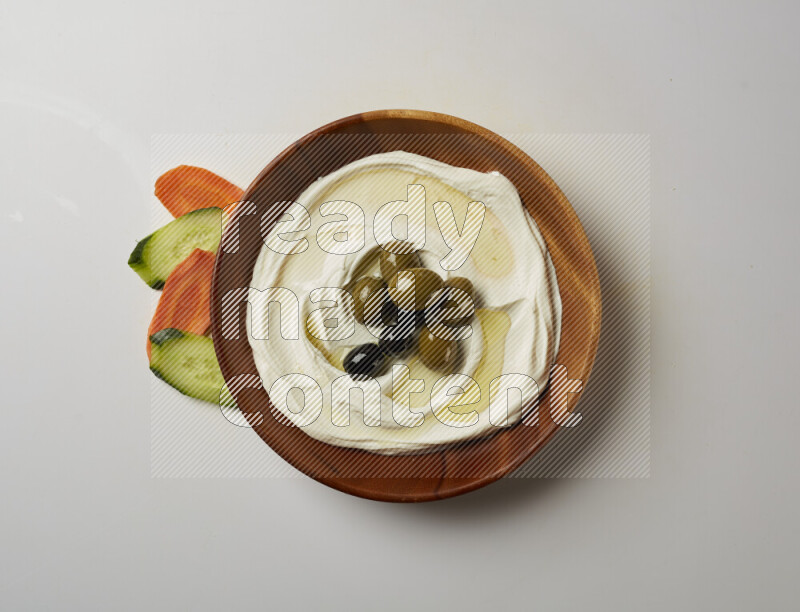 Lebnah garnished with whole olives in a wooden plate on a white background