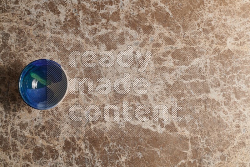 A multicolored pottery bowl on beige marble background